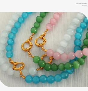 Macro shot of colorful beaded necklaces with textured gold spring ring clasps and cat eye stones