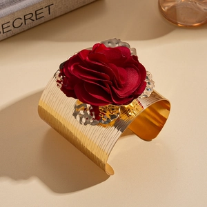 Detailed macro view of a large dark red fabric flower on a brushed gold metal arm cuff