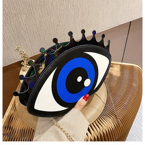 Detail of creative big eye crossbody bag with golden chain and colorful top accents