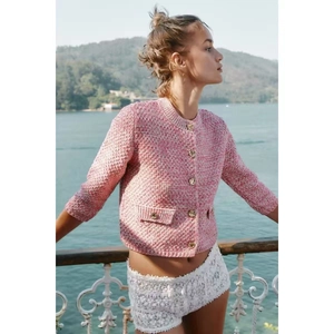 Detail of pink and white tweed cardigan featuring gold embossed buttons and fringe pockets