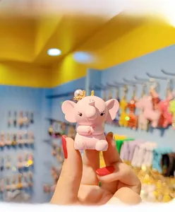 Close-up of pink elephant charm with golden crown and pearl detail held in hand