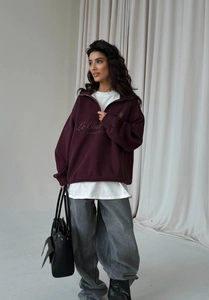 Detail of burgundy quarter-zip sweatshirt with Le Club embroidery and high-waist jeans