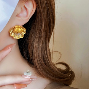 Close-up of vintage golden shell earring with pearl on model's ear in french style