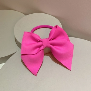 Detail of a bright pink ribbed bow hair tie showing high-density fabric texture