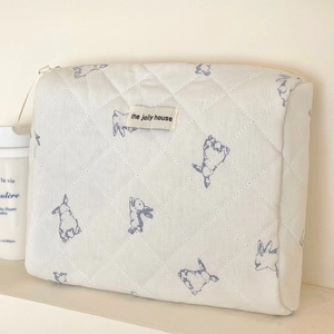 Detailed close-up of quilted cotton cosmetic bag with cute rabbit pattern and logo tag