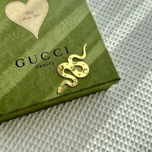 Detail view of a golden snake ornament on a green textured vintage gift box