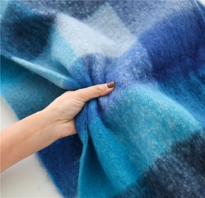 Close-up of thick blue plaid scarf showing soft fuzzy texture and high-density knitting