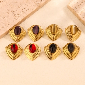 Close-up of vintage gold stud earrings with oval colorful gemstones on marble stone