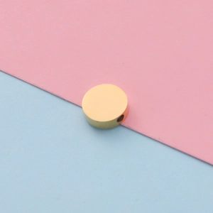 Detailed view of a 10mm polished golden stainless steel bead on a split pastel background
