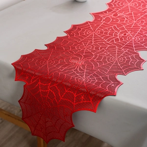 Close-up of red spider web hollow lace table runner on a long grey table