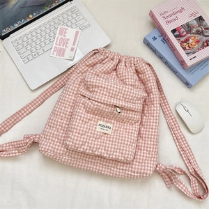 Detailed view of pink heart-quilted gingham backpack with drawstring and study props