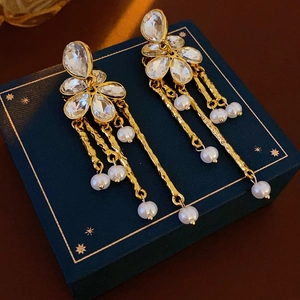Detail of vintage flower stud earrings with golden tassels and white pearl drops