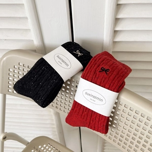 Japanese style grey crew socks with cute bow embroidery on a cozy chair