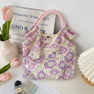 Close-up of floral tote bag featuring a snap button and colorful woven handles