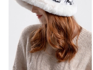 Close-up of white faux fur winter bucket hat with plush texture and knit sweater detail