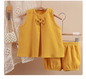 Détail d'ensemble en gaze de coton jaune pour bambin montrant le tissu respirant et nœud