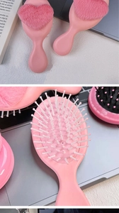 Detail of pink massage comb showing soft plush heart decor and white rounded plastic bristles