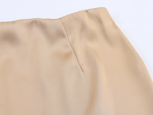 Macro detail of glossy champagne satin fabric and high-quality stitching on the skirt