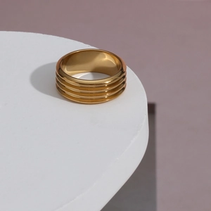 Close-up of golden multi-layer ribbed stainless steel ring on a white display stand