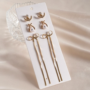 Set of 3 gold butterfly bow earrings with pearls and rhinestones on satin background