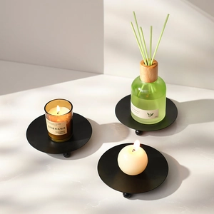 Three-piece set of black round metal aromatherapy candle holders on marble surface