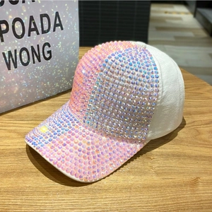 Detailaufnahme der weißen Baseballkappe mit pinkfarbenen Strasssteinen auf Holzständer