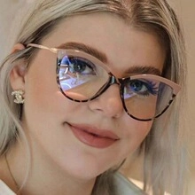 Close-up of stylish pink and leopard cat-eye sunglasses worn by a model in soft indoor lighting