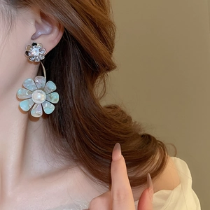 Detail of floral earrings with pearl center and iridescent petals on a model