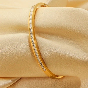 18K gold plated bangle with rectangular cut zircon inlay on satin gold fabric background