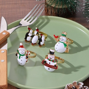 Detail of Christmas napkin rings with penguins and snowmen on a festive dinner plate