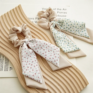 Detail of floral print hair scrunchies with long ribbons in beige satin finish