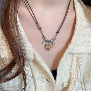 Close-up of retro wooden rocking horse necklace worn on a cream knit cardigan
