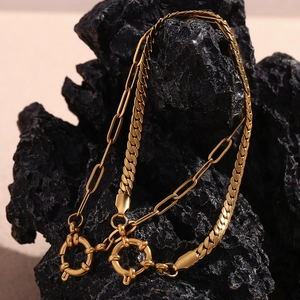 Detail of 18K gold-plated paperclip and curb link bracelet on black volcanic rock