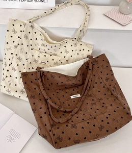 Detail of cream and brown corduroy tote bags with heart and bow patterns in a lifestyle setting