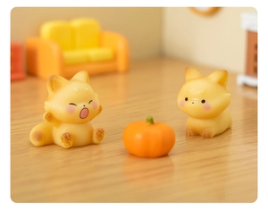 Detail of two mini resin foxes with a pumpkin on a wood surface in micro landscape style