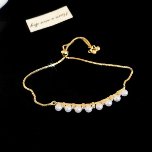 Detail of adjustable gold-plated slider bracelet with white pearls and zirconia accents