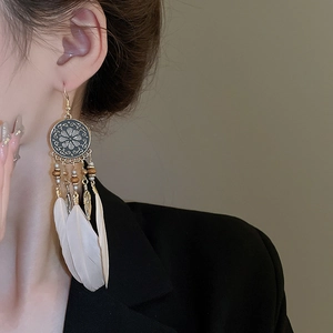 Macro shot of long bohemian earrings with bronze metal, wood beads and white feathers