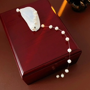 Macro detail of natural freshwater pearls and iridescent shell charm on a vintage jewelry box