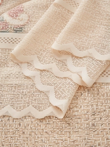 Close-up of beige lace curtain featuring floral prints and scalloped wavy edges