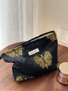 Detail showing high-quality gold butterfly embroidery on black canvas cosmetic bag