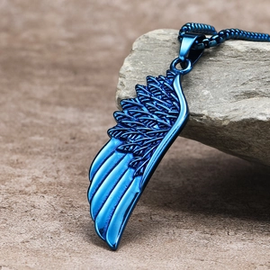 Macro shot of blue titanium steel wing pendant with feather texture on a rock