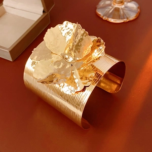 Macro detail of golden flower cuff with hammered metal texture and ribbed band