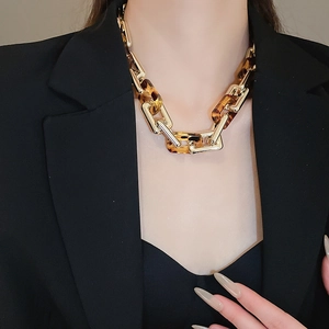 Dettaglio di una collana a catena dorata con maglie in resina tartarugata indossata