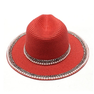 Detailed top view of red straw hat featuring white pearl and silver stud embellishments