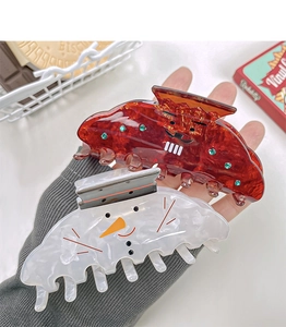 Close-up of Christmas snowman and red amber textured hair claws with rhinestone details