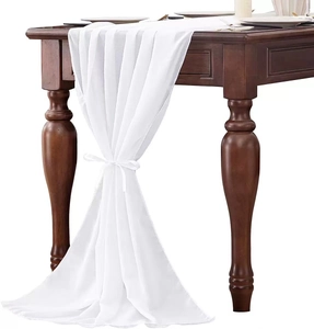 Close-up of white chiffon table runner with elegant bow knot on dark wood table