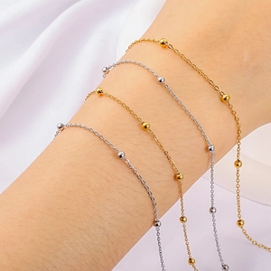 Minimalist gold and silver stainless steel beaded cross chains worn on a wrist