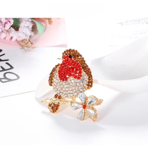 Detailed view of an alloy bird brooch with red rhinestones on a golden branch