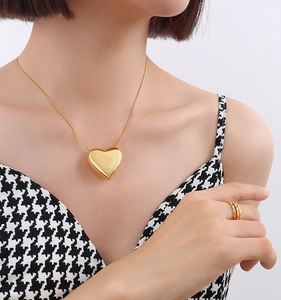 Detailed view of a 3D heart-shaped gold pendant necklace worn by a female model