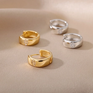 Detail of gold and silver hoop earrings with circular zircon settings on silk fabric